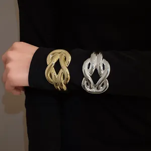 Close-up of bold gold and silver metallic horseshoe knot chunky bangles worn on sleeve
