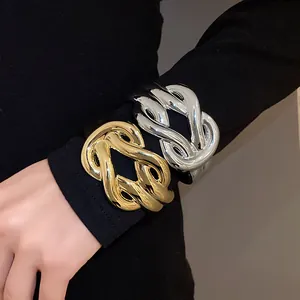 Retro chunky gold and silver intertwined knot acrylic bangles worn over black sleeve detail