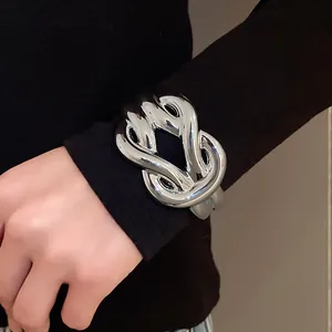 Detailed view of a chunky silver acrylic horse-bit bracelet styled over a black sleeve