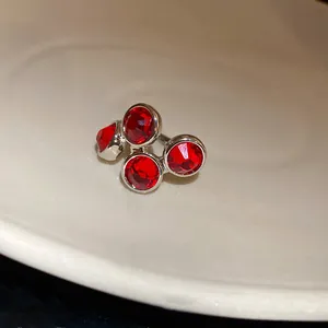 Primer plano de un clip de oreja vintage plateado con cuatro cristales rojos redondos