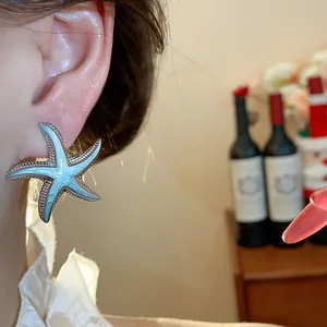 Detailed view of a light blue starfish stud earring with silver textured edges.