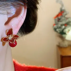 Detail shot of red flower stud earrings with pearl drop on ear for festive look.