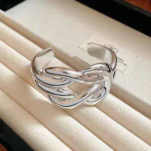 Close-up detail of a silver-toned wide intertwined cuff bracelet in a jewelry tray