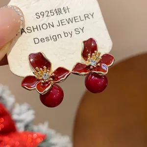 Close-up of elegant Ancora red resin flower stud earrings with a pearl drop detail
