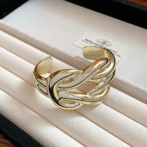 A detailed close-up shot of a wide gold horseshoe buckle cuff on a jewelry tray