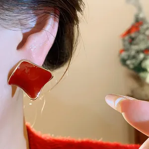 Detailed view of elegant red resin square stud earrings with gold trim worn on ear