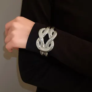 Detail view of a chunky silver oversized knot buckle acrylic bracelet on a model's wrist