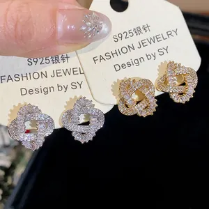 Detailed close-up of 18k gold-plated intertwined stud earrings with zircons