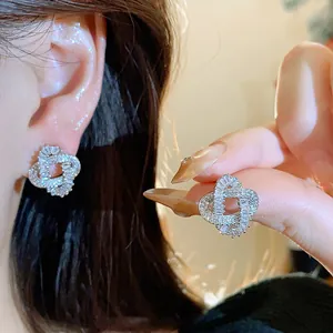 Elegant close-up shot of sparkling zircon intertwined stud earrings worn on ear