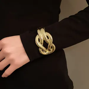 Close-up of a chunky gold acrylic horseshoe buckle bracelet on a black sleeve.