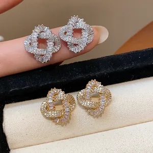 Detailed macro view of gold and silver intertwined knot stud earrings with cubic zirconia stones.