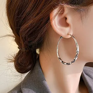 Elegant silver twisted hoop earrings worn by a model for a sophisticated look.