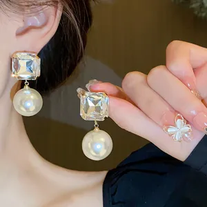 Close-up of elegant French style earrings with square crystal and large pearl detail