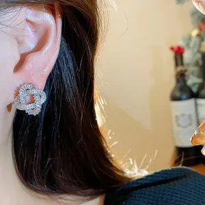Detail shot of 18k gold plated silver needle intertwined zircon earrings worn on ear