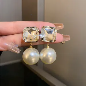 Detailed close-up showing texture of square crystal and round pearl drop earrings