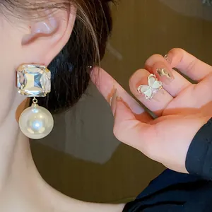 Close-up view of French style square rhinestone pearl earrings worn on an Asian model.
