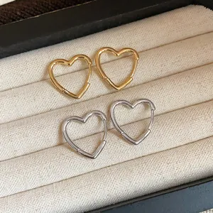 Detail shot of gold and silver heart-shaped hoop earrings in a jewelry box