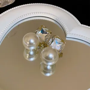 Detailed macro shot of elegant square crystal and pearl stud earrings on a heart mirror.