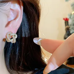 Close-up of 18k gold plated entwined stud earrings with sparkling zircon on ear