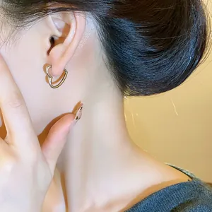 Detailed view of a minimalist silver-tone heart-shaped hoop earring worn on the ear