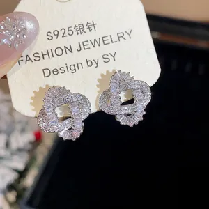 Close-up detail of silver needle stud earrings with intertwined zircon pave design