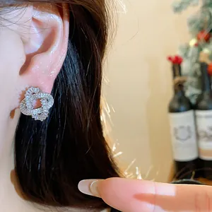 Detailed view of intertwined zircon stud earring with silver needle on an Asian model