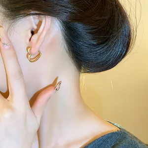 Close-up of minimalist heart-shaped gold hoop earring worn on model's ear