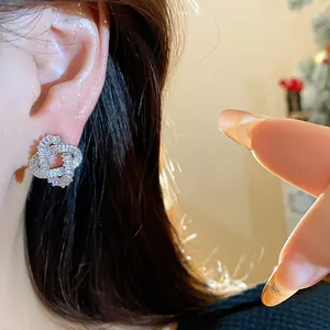 Detailed view of elegant sparkling entwined zircon stud earrings on model's ear