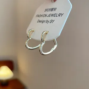 Close-up of minimalist gold-colored heart-shaped hoop earrings on display card