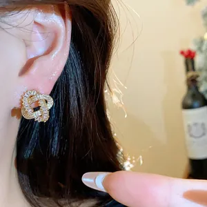 Close-up of 18k gold plated entwined stud earrings with sparkling zircon stones