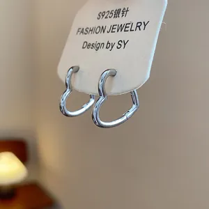 Close-up view of minimalist heart-shaped silver hoop earrings with a glossy finish
