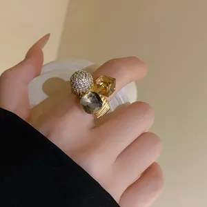 Detail view of a gold-plated open ring featuring zircon pave ball and colorful crystals.