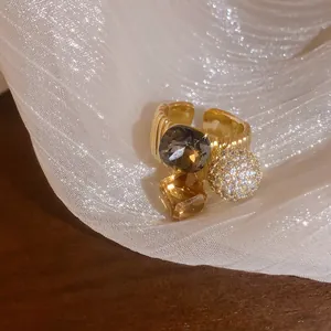Macro view of gold-plated ring featuring grey and amber square stones with sparkling zircon ball.