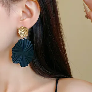 Detailed macro view of black mint leaf drop earrings with hammered gold studs