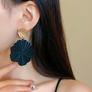 Elegant black pleated mint leaf dangle earrings with gold hammered finish worn by model
