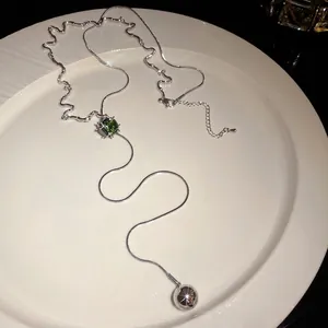 Elegant silver adjustable zircon square necklace with ball tassel on white porcelain plate.