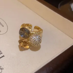 Detailed close-up of gold-plated open ring featuring a large crystal and pave zircon ball