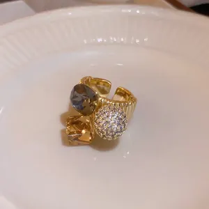 Macro detail of a gold-plated adjustable ring featuring sparkling zircon and multi-colored crystals