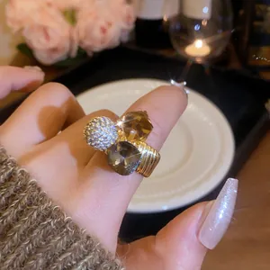 Detailed macro view of a gold-plated statement ring featuring sparkling zircon and brown crystals.