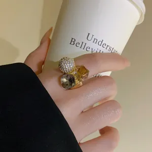 Detailed view of luxury gold plated zircon crystal open ring on finger holding a cup