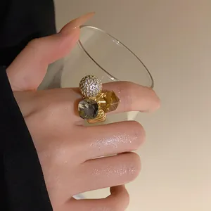Close-up of a gold-plated ring with zircon and geometric crystals on the finger.