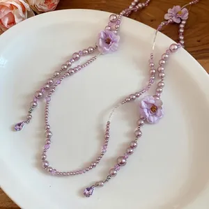Elegant purple pearl necklace featuring fabric flowers and delicate tassel fringe - 81 chars.