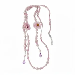 Long pearl necklace featuring delicate pink fabric flowers and purple crystal teardrops.