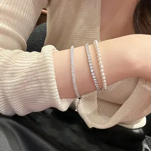 Close-up of elegant zircon mesh, tennis and pearl bracelet set worn on a female wrist.