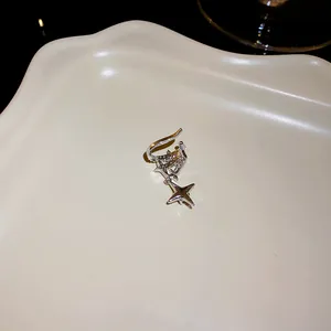 Close-up detail of a minimalist silver zirconia star ear cuff with sparkling dangling charms.