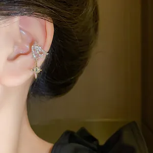 Close-up of sparkling zircon star ear cuff earring with an elegant dangling cross star