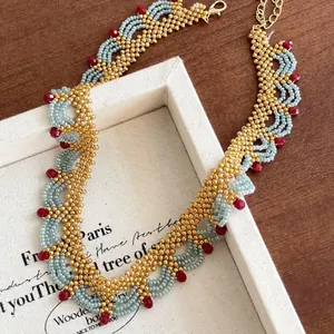 Collier ethnique fait main avec des perles de verre dorées bleues et cristaux rouges