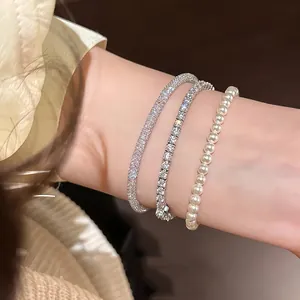 Close-up detail view of elegant silver zircon mesh, tennis, and pearl bracelet stack