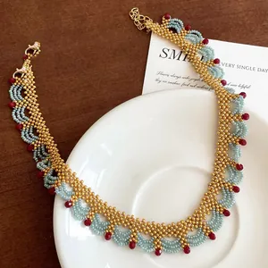 Collier ethnique fait main avec perles en tons or, bleu clair et rouge rubis élégant