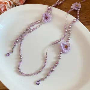 Close-up of elegant purple pearl necklace with fabric flowers and crystal drops.